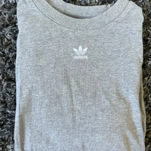 Grå Adidas t-shirt  - Säljer en grå t-shirt från Adidas. T-shirten har rund halsringning med ribbad kant. 