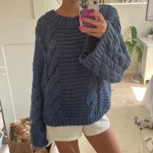 Blå chunky stickad tröja - Mysig chunky stickad tröja i mörkblått med grova flätstickade detaljer och breda ärmar. Perfekt för kyliga dagar och ger en avslappnad oversized vibe. Tröjan har rund halsringning och är riktigt skön att bära.
