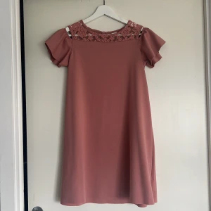 Rosa barnklänning med spetsdetalj - Söt rosa barnklänning med off-shoulder ärmar och spets upptill. Näst intill oanvänd!