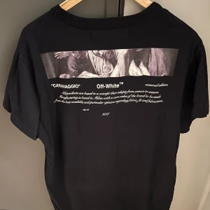 Off-White Caravaggio t-shirt - Virgil Abloh - Svart t-shirt från Off-White med trycket "02" framtill och Caravaggio-motiv på ryggen. 