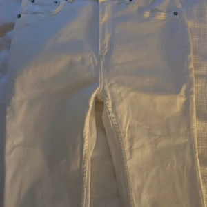 Vita skinny jeansbyxor - Snygga vita jeansbyxor med klassisk femficksmodell och skinny ben. Byxorna har bälteshällor och silverfärgade nitar vid fickorna. Perfekta för en clean och fräsch look året runt.