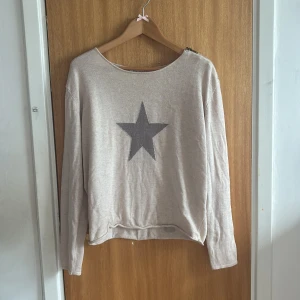 Beige stickad tröja med stjärna - Beige stickad tröja från Choklate med en stor grå stjärna framtill. Tröjan har rund halsringning och långa ärmar. Perfekt för dig som gillar en chill och enkel stil med en liten twist💗Skulle säga att tröjan är en M/S?