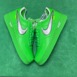 Nike Air Force 1 Off-White Grön/Silver - Nike Air Force 1 x Off-White sneakers i en riktigt grön färg med metallic silver swoosh och tydliga Off-White-detaljer. Skorna har snörning, låg profil och textdetaljer på sidan. Ovandel i skinn och klassisk platt sula. Perfekta för dig som vill sticka ut. Finns i all storlek 