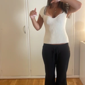 Vit ribbad topp från H&M - Säljer en vit ribbad topp från H&M med snygg uringning och korta ärmar. Toppen är figurnära och stickad i mjukt material som ger en skön känsla. Perfekt att styla med jeans eller kjol för en clean och fräsch look.