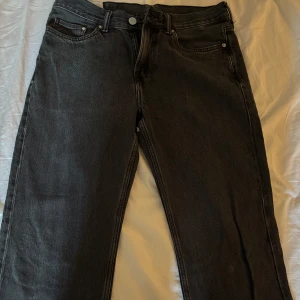 Svarta relaxed jeans från &Denim - Svarta jeans från &Denim i relaxed fit med klassisk femficksdesign och knappgylf. Jeansen har rak siluett och är tillverkade i slitstarkt denimtyg. Perfekt för dig som gillar en chill och loose stil. Storlek 31/30.