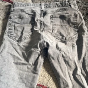 Grå jeans SIS by Sisters Point - Säljer ett par grå jeans från SIS by Sisters Point med klassisk femficksdesign och snygga slitna detaljer vid bensluten. Jeansen har rak passform och dragkedja i gylfen. Perfekt för dig som gillar en chill och avslappnad stil.