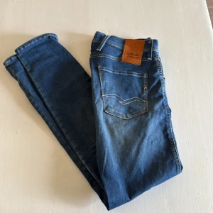 Replay Anbass Hyperflex jeans blå 29 - Snygga Replay Anbass Hyperflex jeans i klassisk blå färg med lätt slitning. Pris kan diskuteras vid snabb affär.
