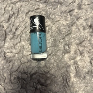 GOSH blått nagellack - Snyggt blått nagellack från GOSH i en stilren glasflaska med svart lock. Perfekt för dig som vill ha en cool och trendig färg på naglarna. Lätt att applicera och ger ett jämnt resultat med pro finish.