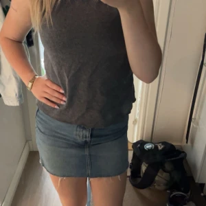 Blå jeanskjol med fransig kant - Säljer en blå jeanskjol från 157 med klassisk femficksdesign och fransig, rå nederkant. Kjolen är kort och har bälteshällor samt knapp spänning