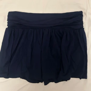 Mörkblå kortkjol  - Supersnygg mörkblå kortkjol med rynkad midja från Nelly. Den är i storlek XS. Helt oanvänd! 