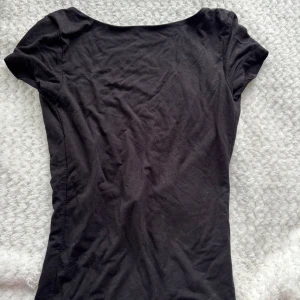 Svart topp från Gina Tricot - Säljer en svart tajt T-shirt med öppen rygg ifrån Gina tricot, den har storleken XS och är nästan aldrig använd🌸