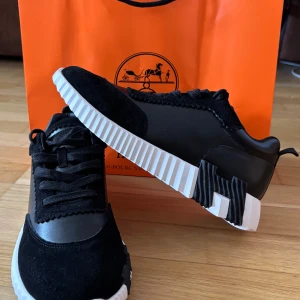 Svarta sneakers från H3rmes - Snygga svarta sneakers med cool vit och svart räfflad sula och H-detalj undertill. Ovandelen är i en mix av mocka och skinn, med snörning och rund tå. Perfekt för dig som gillar exklusiva och trendiga skor med unik design. Pris går att diskuteras. Tveka inte på att fråga. 
