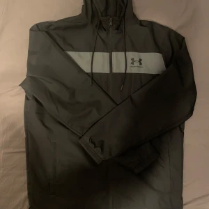 Under Armour Windbreaker - Mörkblå (nästan svart) Under Armour windbreaker, strl M. Endast använd ett fåtal gånger – toppskick! Pris kan diskuteras vid snabb affär. Nypris 849kr