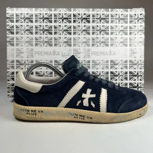 Blå sneakers från Premiata - Snygga blå sneakers från Premiata med vita detaljer och snörning. Skorna har en rund tå och är tillverkade i mocka med en kontrasterande beige sula. Perfekta för en stilren look. 💯 %äktihetsvarifierad nypris 4999 vårt pris 2899 vid snabb affär kan det ändras