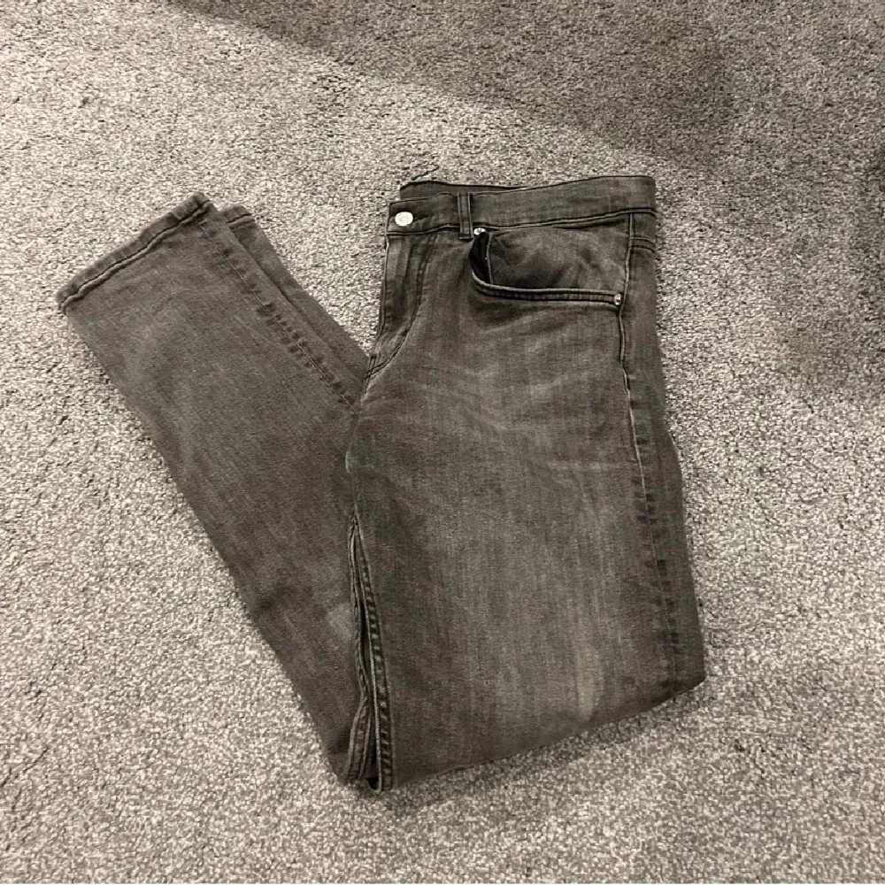 Snygga grå jeans från J.Lindeberg i en klassisk stil. De har en normal passform och är perfekta för en stilren look. Jeansen har en knapp och dragkedja framtill samt fem fickor.. Farkut & Housut.