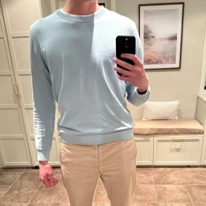 Ljusblå tröja från Oscar Jacobson - Säljer en stilren ljusblå tröja från Oscar Jacobson. Tröjan har en klassisk rund hals och långa ärmar, perfekt för en avslappnad men ändå elegant look. Passar bra till både jeans och chinos.