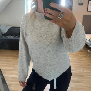 Grå stickad tröja - Mysig grå stickad tröja med rund hals och långa ärmar. Perfekt för kyligare dagar och enkel att matcha med olika outfits.
