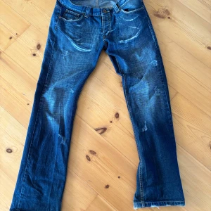  Angel devil  - Snygga blå jeans med unikt vingmotiv på bakfickorna. De har en klassisk femficksdesign och slitna detaljer för en cool look. Perfekta för dig som vill sticka ut!