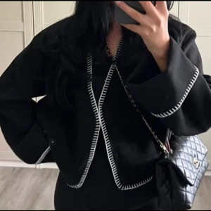 Svart kofta Ginatricot  - Superfin svart kofta med vita detaljer från Gina trot. Bara använt ett fåtal gånger så i superfint skick 