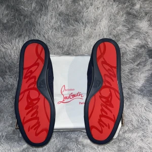 Blåa sneakers från Christian Louboutin - Snygga blåa sneakers från Christian Louboutin med den ikoniska röda sulan. Skorna har snörning och en elegant design som passar perfekt för en stilren look.
