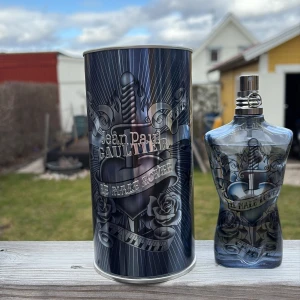 Le Male Lover av Jean Paul Gaultier - Säljer en flaska Le Male Lover Eau de Parfum från Jean Paul Gaultier. Flaskan har en unik design i form av en manlig torso med ett mörkt, stilrent mönster. Parfymen kommer i en metallisk cylinderförpackning. Flaskan har ungefär 120 ml kvar och är perfekt för den som vill ha en distinkt och maskulin doft. Den är använd fåtal gånger och passar perfekt året runt.