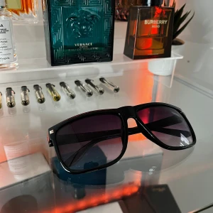 Solglasögon - Snygga svarta solglasögon med bred båge och mörka linser. Perfekta för en stilren look. Passar både till vardag och fest.