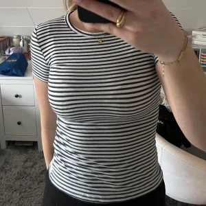 Randig t-shirt - Säljer en klassisk randig t-shirt i marinblå och vit. Den har en tight passform och korta ärmar med ett mjukt material.