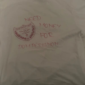Vit t-shirt med tryck - Pris kan diskuteras så skicka prisförslag. Säljer en vit t-shirt med rosa text på ryggen 'Need money for Dom Perignon'. Perfekt för den som vill ha en rolig och avslappnad stil. T-shirten är gjord av bomull och har en normal passform. Använd 1 gång. 