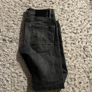Grå jeans med slim straight fit - Snygga grå jeans från Jack and Jones med en slim straight passform. De har en klassisk femficksdesign och en knappgylf. Perfekta för en stilren look. Passar folk från 168 till 180. Skriv vid några frågor.