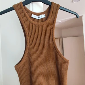 Brun Adoore klänning i storlek 34 - Jättefin härlig brun klänning från märket Adoore. Storlek 34. Väldigt stretchig i materialet! Klassisk "brottarskurning". Slits längst ner bak på klänningen. Markerad midja i form av annan stickning i midjepartiet. Otroligt fin kvalitet, syns inte ens att den blivit använd.