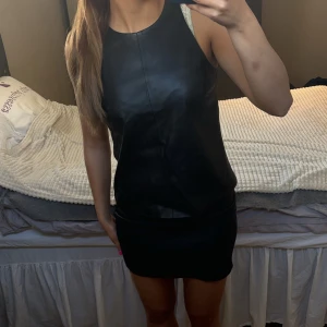 Svart topp i skinnimitation - Snygg svart topp i skinnimitation med ärmlös design. Perfekt för en kväll ute eller en speciell tillställning. Från Zara i strolek S/36. Endast använd ett fåtal gånger, säljes pga att den inte kommer till användning. 