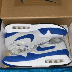 Nike Air Max 1 '86 OG i vit och blå - Säljer ett par klassiska Nike Air Max 1 '86 OG sneakers i vit och royal blå. Skorna har en ikonisk design med synlig Air-enhet i sulan och snörning framtill. Perfekta för både stil och komfort. Använda engång (testade)