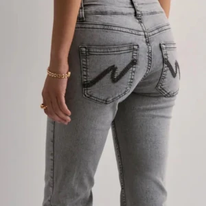 Grå jeans med broderad detalj från Nelly - Snygga grå jeans från Nelly med en unik broderad detalj på bakfickorna. De har en låg midja och bootcut-stil som ger en trendig look. Helt nya, direkt ut paketet. Nypris: 699kr