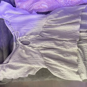 Vit blus - Charmig vit blus med knytning framtill och volangdetaljer. Perfekt för sommarens varma dagar. Den har en luftig passform och korta ärmar.