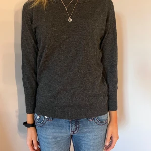 Mörkgrå tröja - Säljer en stilren mörkgrå tröja med lång ärm. Perfekt för kyligare dagar och lätt att matcha med olika outfits. Tröjan har en klassisk passform och är tillverkad i ett mjukt material.