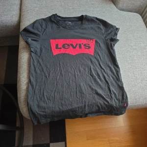 Svart t-shirt från Levi's - Säljer en svart t-shirt från Levi's med deras ikoniska röda logga på bröstet. T-shirten är kortärmad och gjord i mjuk bomull. Perfekt för en avslappnad stil. Passar bra till jeans eller shorts!