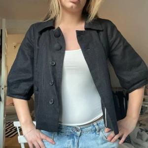 Svart kavaj med trekvartsärm - Snygg svart kavaj med trekvartsärm och knappar framtill. Perfekt till våren/sommaren!