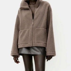 Brun teddyjacka från HM - Mysig brun teddyjacka med dragkedja och stora fickor framtill. Perfekt för kyliga dagar när du vill hålla dig varm och stilren. 