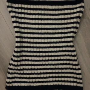 Randig stickad tubtopp - Säljer en stilren randig stickad tubtopp i svart och vit. Perfekt för en trendig look med sin ribbade struktur. Passar bra till både jeans och kjol. Hör av dig vid intresse! Marinblått och vitt helt nytt!! 