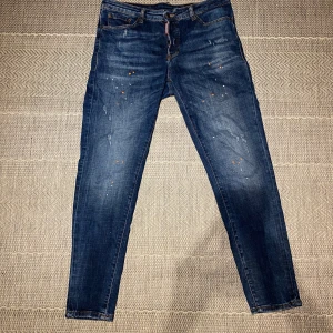 Blå jeans från Dsquared2 - Snygga blå jeans från Dsquared2 med en cool slitningseffekt och orange detaljer. De har en knappgylf. Skick: 9,5/10