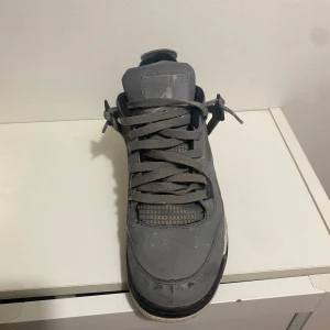 Grå Nike Air Jordan 4 sneakers - Säljer ett par grå Nike Air Jordan 4 sneakers med coola meshdetaljer och svarta inslag på sula och snörhål. Skorna har klassisk snörning och en chunky sula med synlig luftdämpning. Perfekta för dig som gillar streetstyle och vill sticka ut.