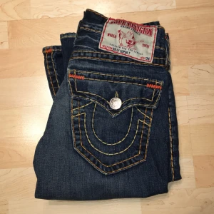 True religion ”Billy super T” - Ett par sällsynta True religon Billy super T jeans. Jeansen är bootcut i storleken W29 (39cm tvärsöver) med innerbenslängd på 80cm. Finns tecken på andvänning med lite heel drag. Var inte rädd med att komma med frågor eller bud!! 