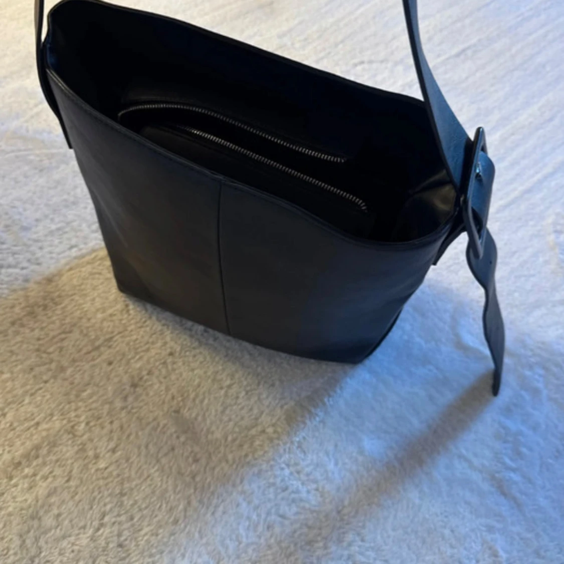 Svart axelväska i imitation av skinn med spänne