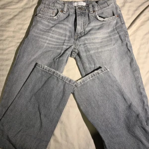 Grå jeans från Zara, raka ben - Säljer ett par ljusgrå jeans från Zara med klassisk femficksdesign och raka ben. Jeansen har normal passform och är tillverkade i bomull. Perfekta för en avslappnad och stilren look.