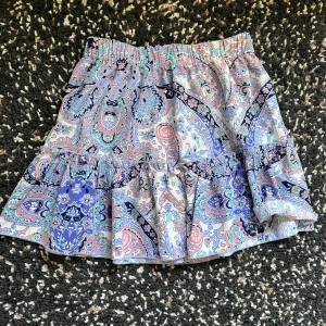 Pastellmönstrad kortkjol från SHEIN - Kortkjol från SHEIN med färgglatt paisleymönster i ljusblått, rosa, mintgrönt och marinblått. Kjolen har volangdetaljer och resår i midjan för skön passform. 