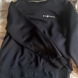 Mörkblå Sail Racing sweatshirt - Snygg mörkblå sweatshirt från Sail Racing med diskret logga på bröstet. Tröjan har rund hals, långa ärmar och ribbade muddar vid ärmslut och nederkant. Perfekt för dig som gillar stilren och sportig look.