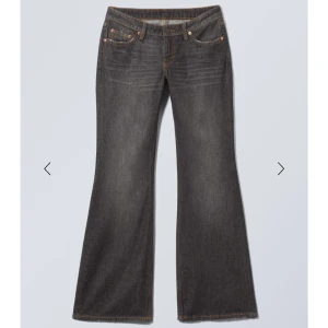 Weekday Nova Low Slim Bootcut Jeans - Snygga mörkgrå bootcut jeans från Weekday i modellen Nova Low Slim Bootcut. Jeansen har låg midja, klassisk femficksdesign och är tillverkade i mjukt denim med orangea sömmar. Perfekta för dig som gillar en retroinspirerad look med utsvängda ben.