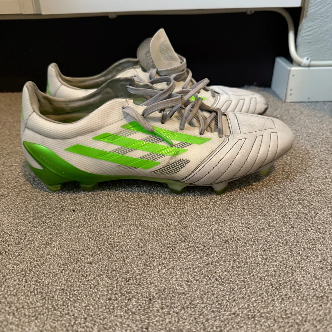 Vita och gröna Adidas fotbollsskor