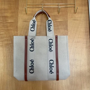 Beige shoppingväska från Chloé - Snygg och rymlig shoppingväska från Chloé i beige canvas med bruna skinn-detaljer. Väskan har breda handtag med Chloé-logga i svart och stilren design. Oanvänd. Nypris är 10000kr.