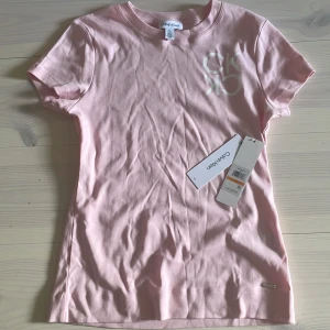 Ljusrosa t-shirt från Calvin Klein - Snygg ljusrosa t-shirt från Calvin Klein med vit CK-logga på bröstet. 